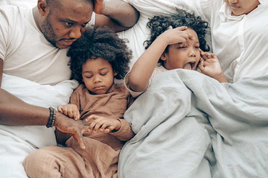 Happy black parents with daughters resting on bed